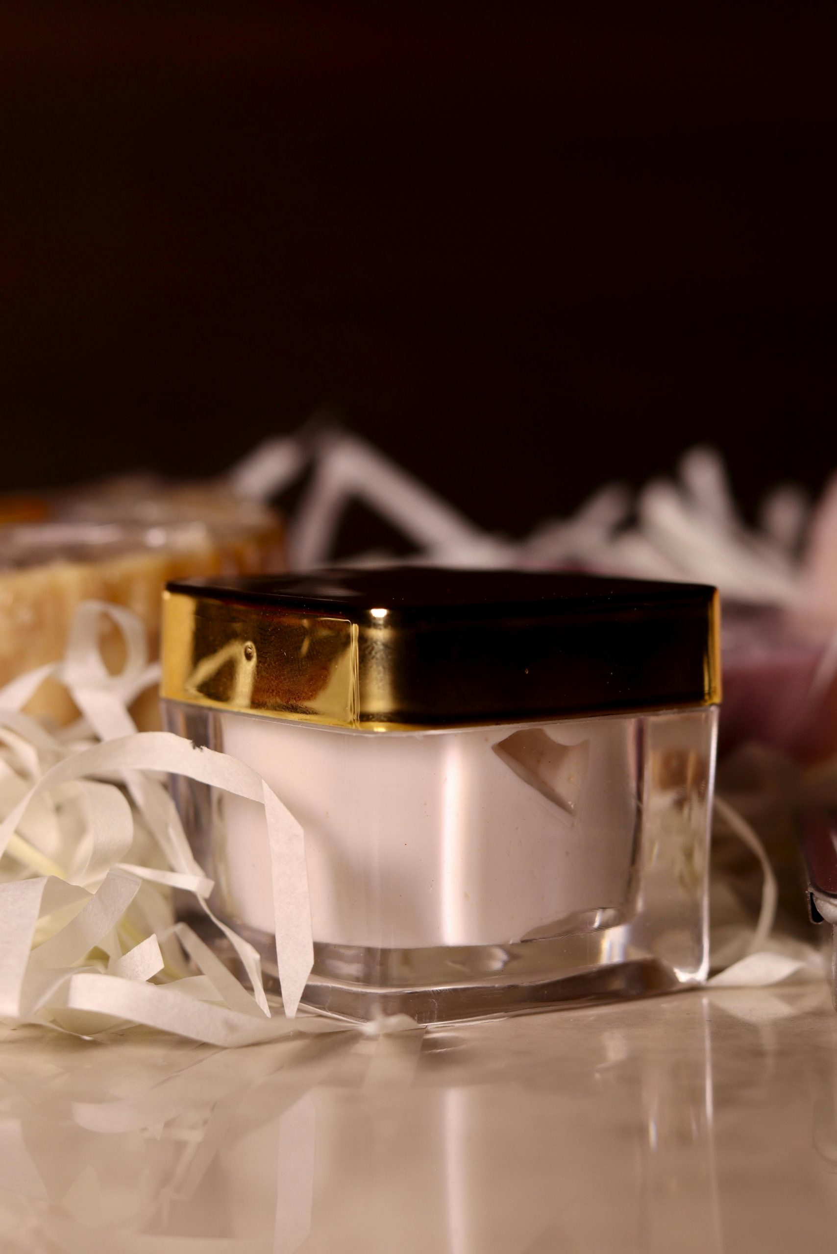 A close-up of a luxurious cream jar surrounded by elegant packaging materials.